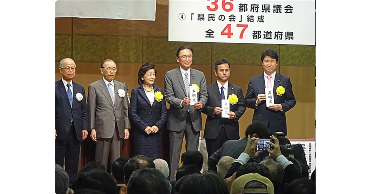 「36都道府県議会『県民の会』結成 全47都道府県」と記された横断幕の前で、白い紙（声明文）を掲げて並ぶスーツ姿の男女6人。