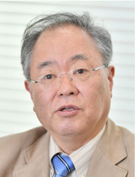 メガネをかけ、淡い色のスーツとネクタイを着用した、白髪混じりの短髪の高橋洋一の顔写真。