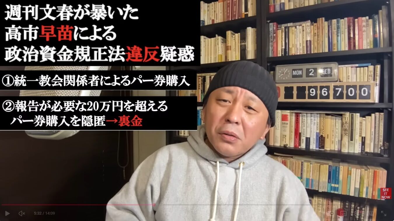 本棚を背景にグレーのパーカーとニット帽を着用した菅野完が語っており、左上に「週刊文春が暴いた高市早苗による政治資金規正法違反疑惑」と書かれたテロップが表示されている。