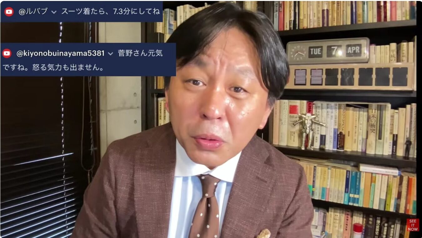 書棚を背にしてスーツを着た男性が、カメラに向かって話しかけている映像のスクリーンショット。