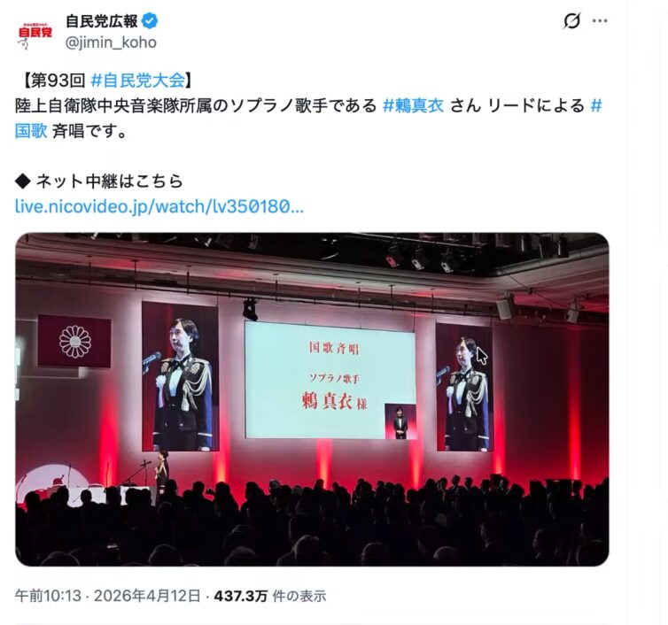 自民党大会のステージ上で、陸上自衛隊中央音楽隊所属のソプラノ歌手・鶫真衣が国歌斉唱を行っている様子。