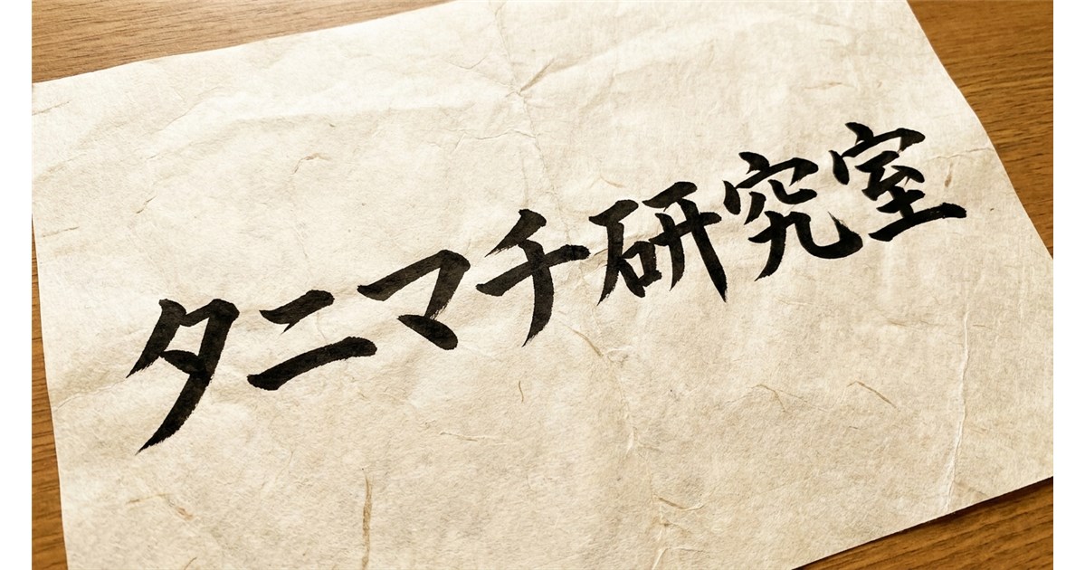 木目調のテーブルの上に置かれた、しわのある和紙に「タニマチ研究室」と黒い墨字で書かれた紙。