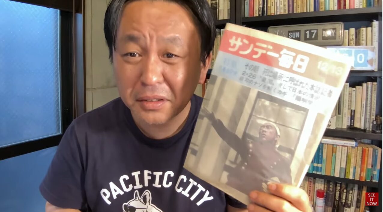 本棚を背にした菅野完が、三島由紀夫が表紙を飾る雑誌『サンデー毎日』を手に持ち、カメラに向かって話している。