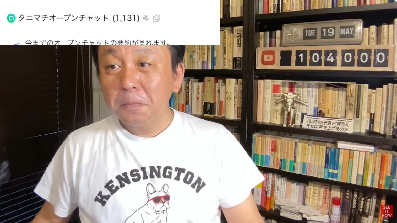 本棚を背景にKENSINGTONと書かれた白いTシャツを着た菅野完。画面上部にタニマチオープンチャットの告知が表示されている。