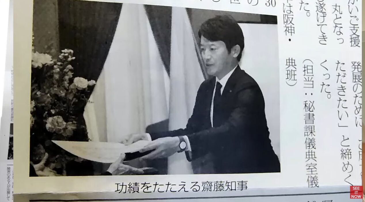 スーツ姿の齋藤元彦知事が、壇上で賞状のような書類を手渡しながら功績をたたえている様子。