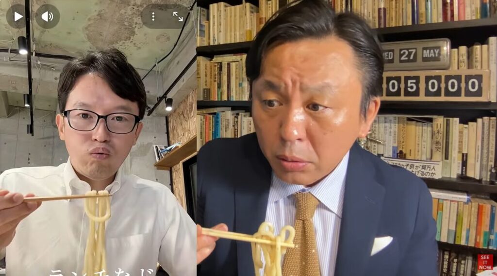 対照的な背景の室内で、それぞれ箸を使ってうどんを口元まで運ぼうとしている二人の斎藤元彦と菅野完の表情を映した動画の場面。