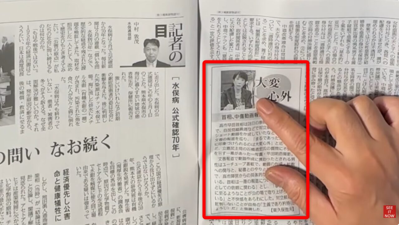 新聞紙面の大変心外という見出しと女性の顔写真が掲載された囲み記事を指差している様子。