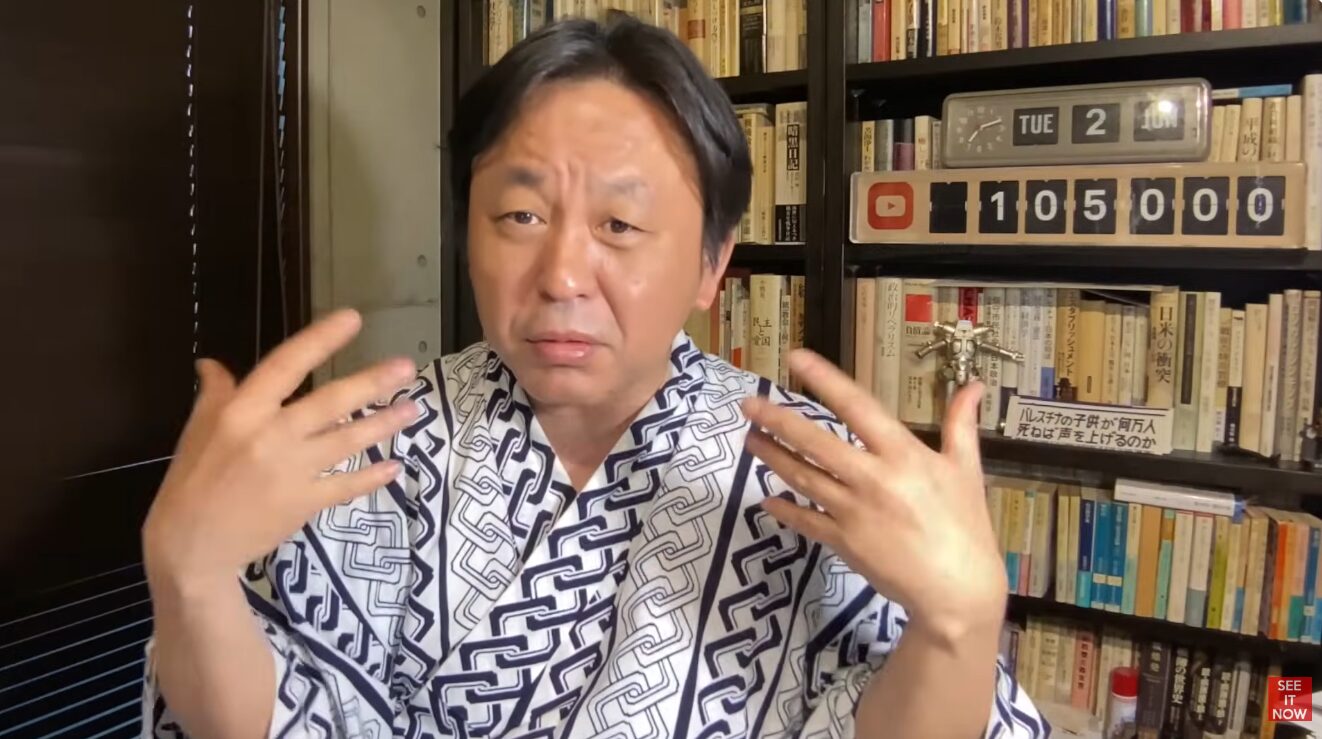 浴衣姿で両手を広げて語りかける菅野完。背景には本棚と105000と表示されたカウンターが置かれている。