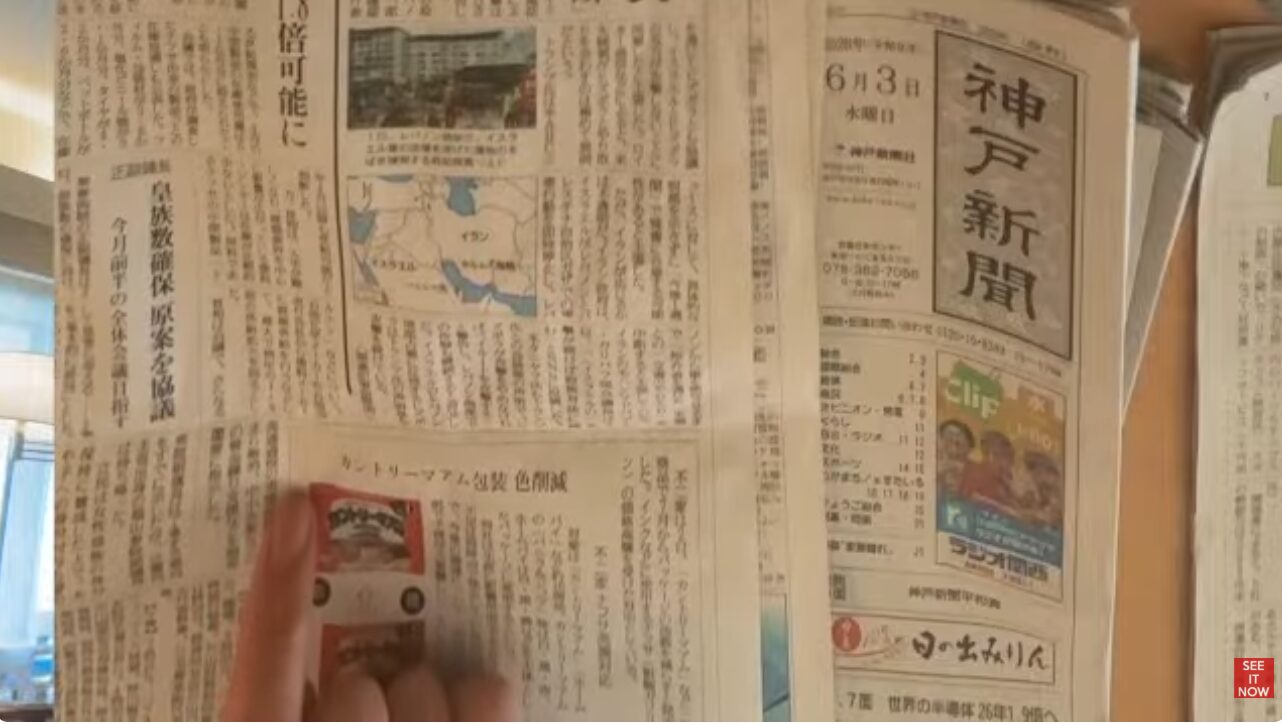 2020年6月3日発行の神戸新聞。カントリーマアムのパッケージ色削減に関する記事を指で示している様子。