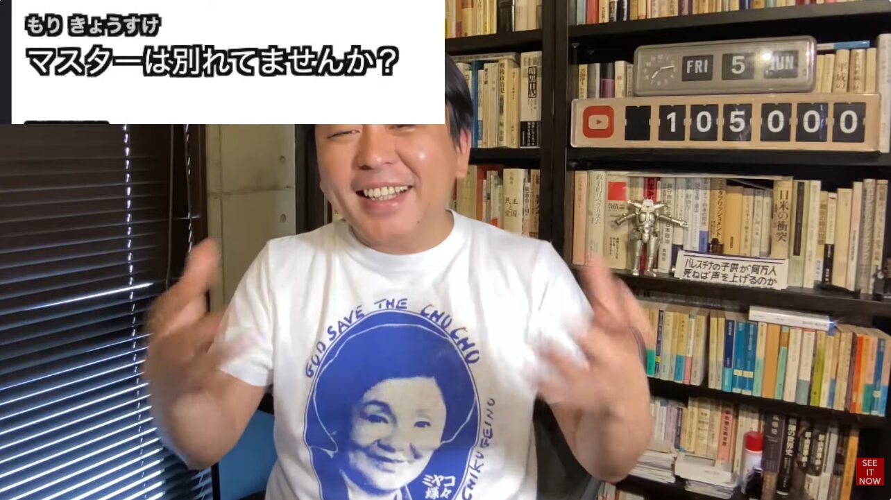もりきょうすけと書かれたテロップを背景に、自身のTシャツについて笑顔で手振りを交えながら語る菅野完。