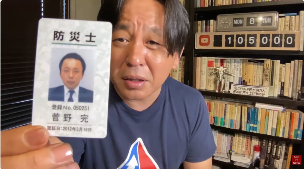 本棚を背景に、菅野完氏が『防災士』と書かれた自身の顔写真付き登録証明書をカメラに向けて提示している。