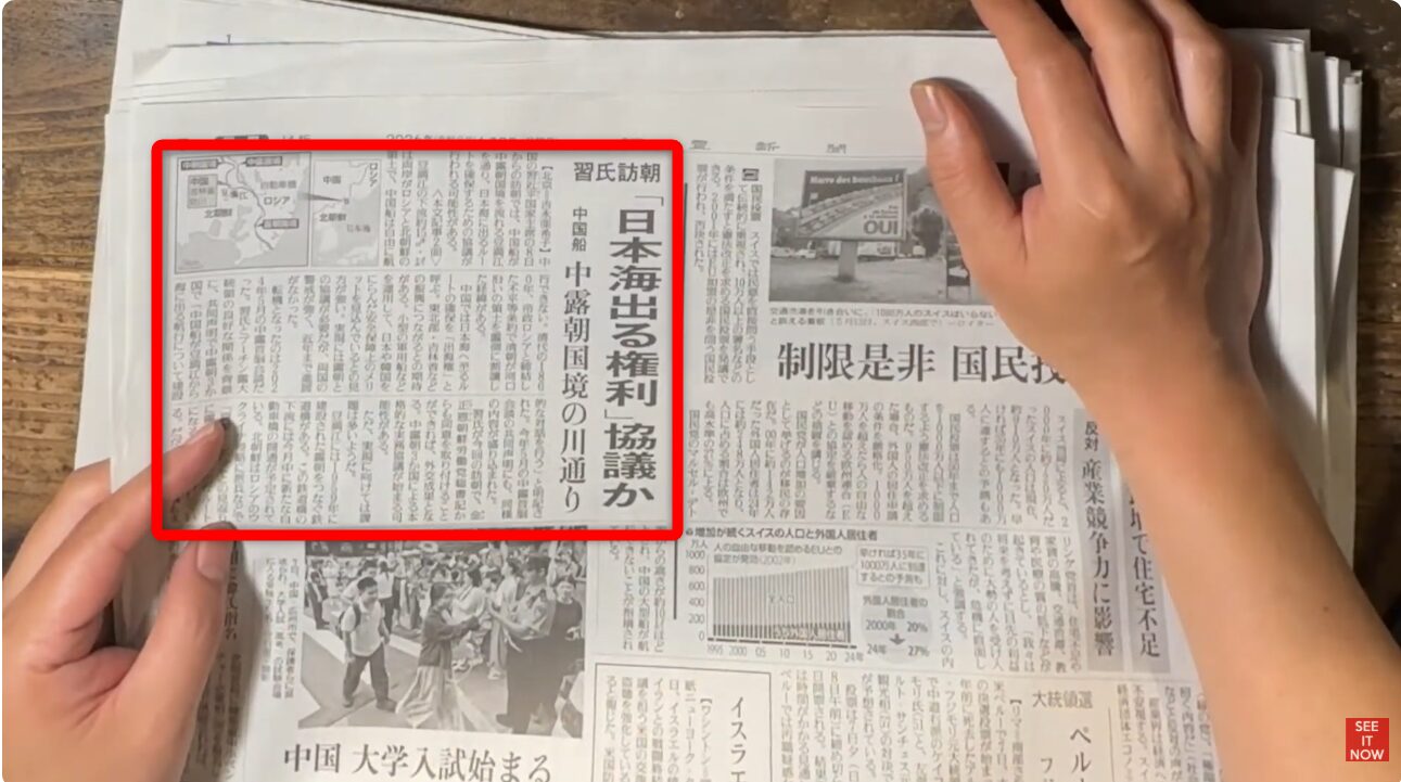 日本海出る権利協議を報じる新聞記事が赤枠で囲まれ、手で広げられている様子。