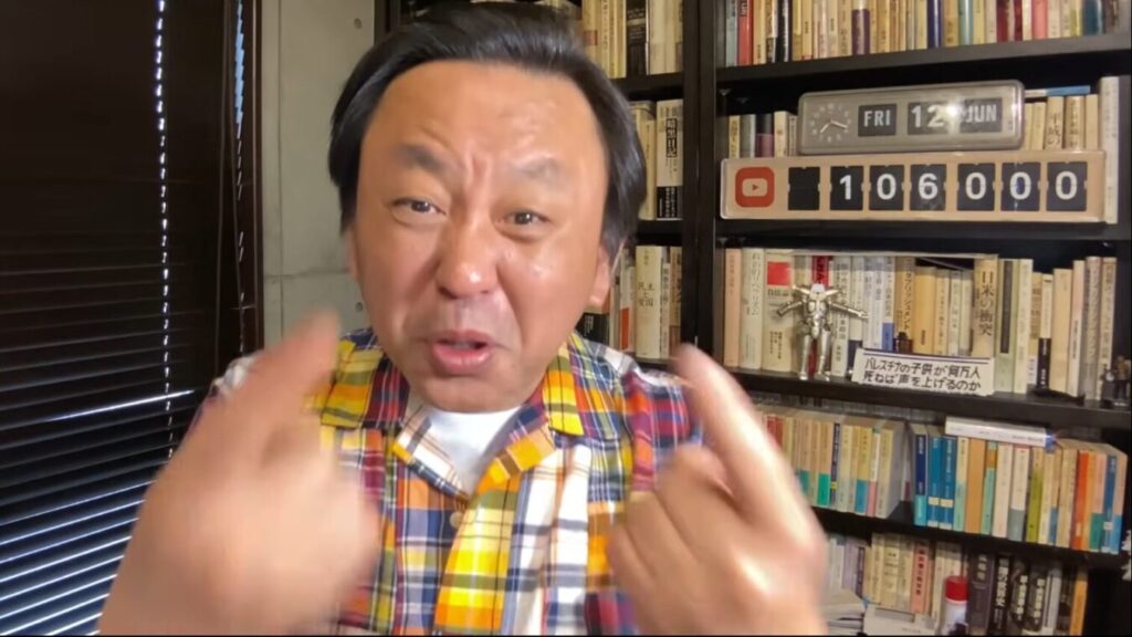 本棚が並ぶ部屋で、カラフルなチェックシャツを着た菅野完が、身振りを交えながら熱心にカメラに向かって話す。