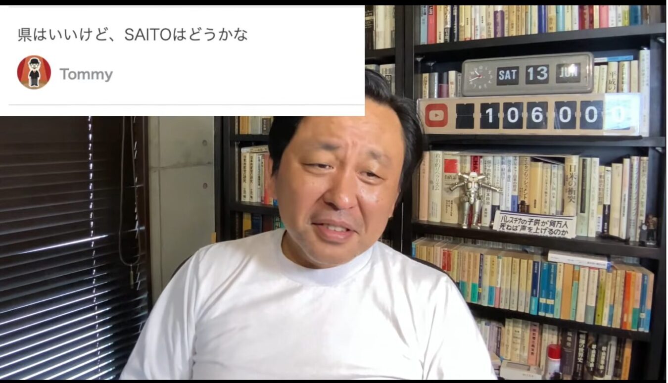 本棚を背景に白いTシャツ姿の菅野完が映る画面上に、県はいいけど、SAITOはどうかなというユーザーからのコメントが表示されている様子。