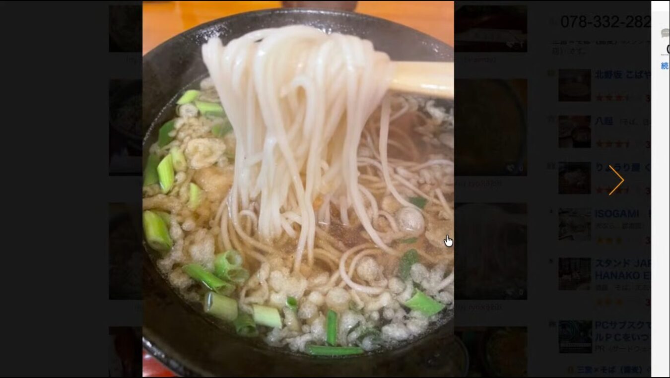 箸で持ち上げられる白く細い蕎麦。天かすと刻みネギがトッピングされた温かい出汁の汁そば。