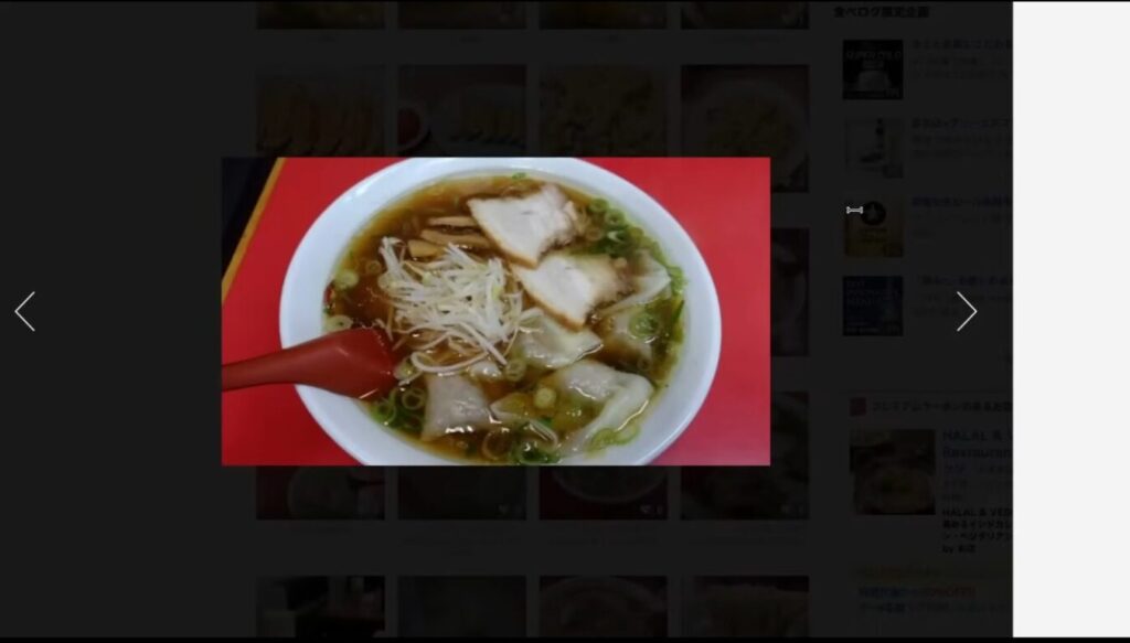 醤油ベースのスープにチャーシューやワンタン、もやしがトッピングされたラーメンを赤いテーブルの上に置いた様子。