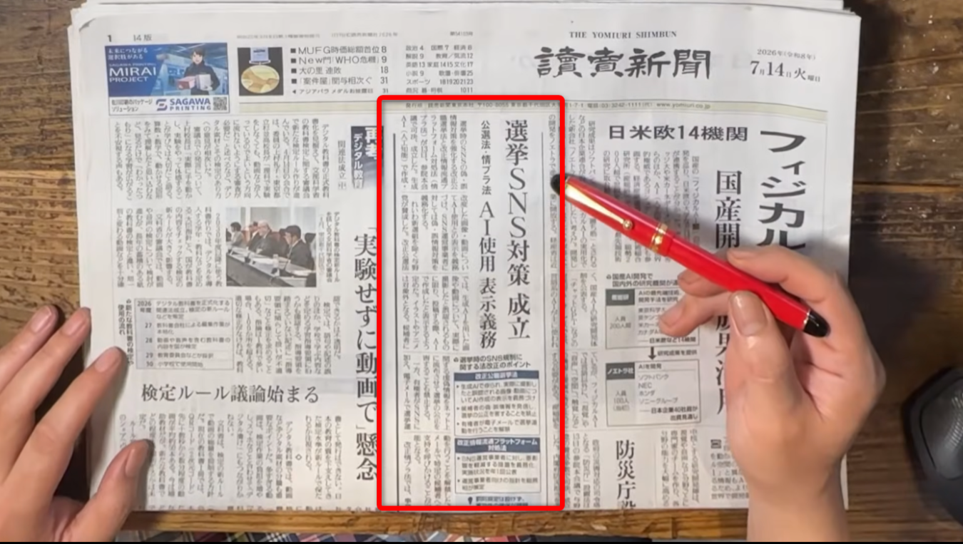 新聞の一面記事に赤色のペンが置かれ、その見出し部分が赤枠で囲まれている。