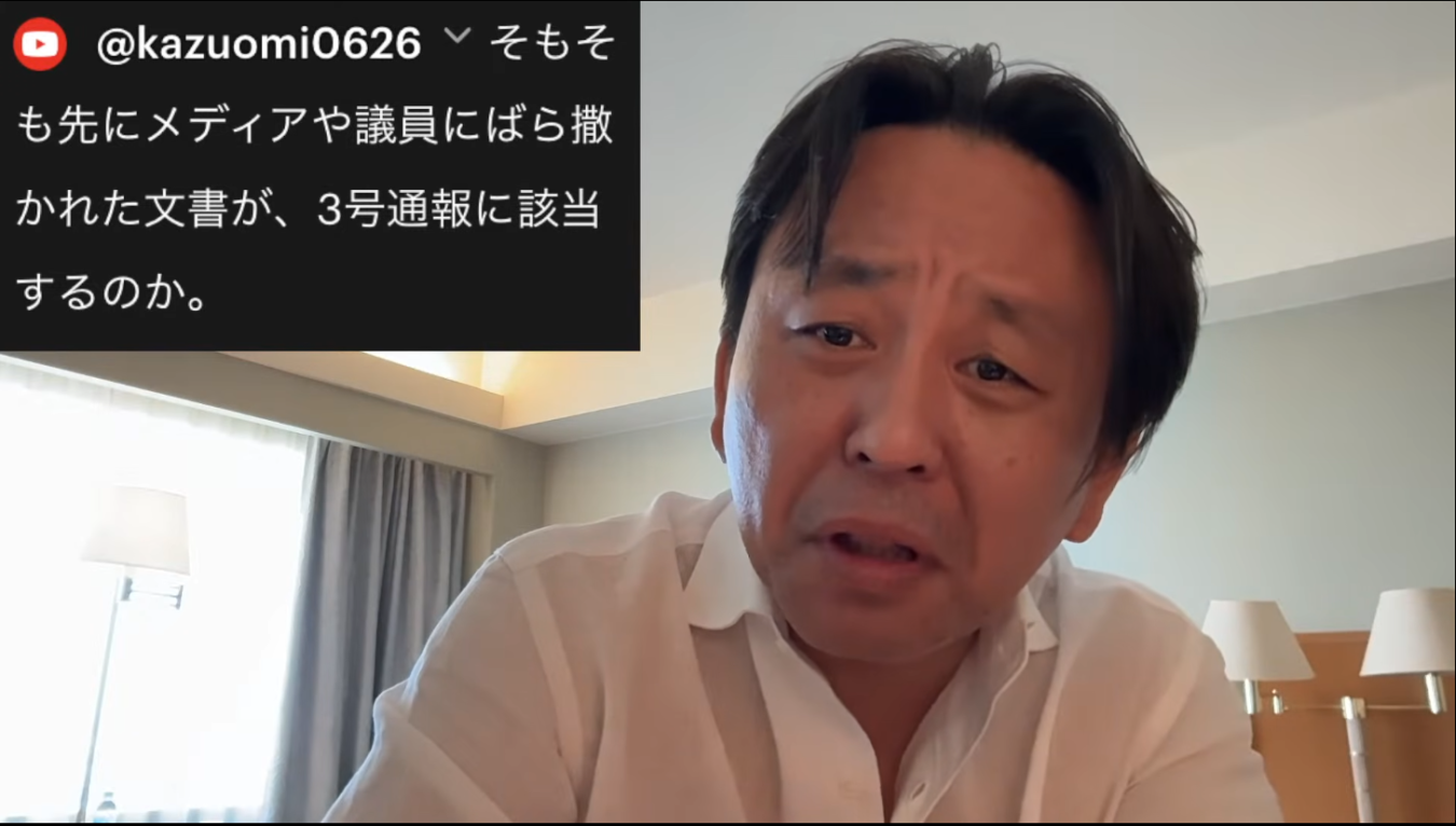 白いシャツを着た菅野完が話し、画面上部に日本語のテキストが表示されている様子