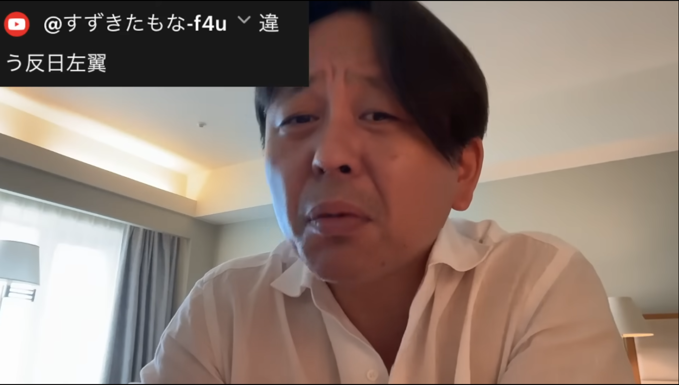 室内で白いシャツを着て話をしている男性と、画面左上の動画配信サービスのコメントが表示された画面