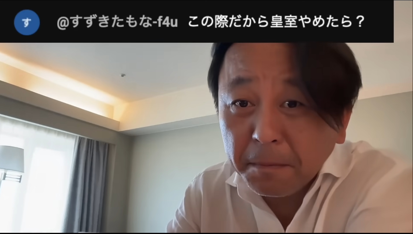 室内で白いシャツを着た男性がカメラを見つめ、上部にライブ配信のコメントが表示されている画像