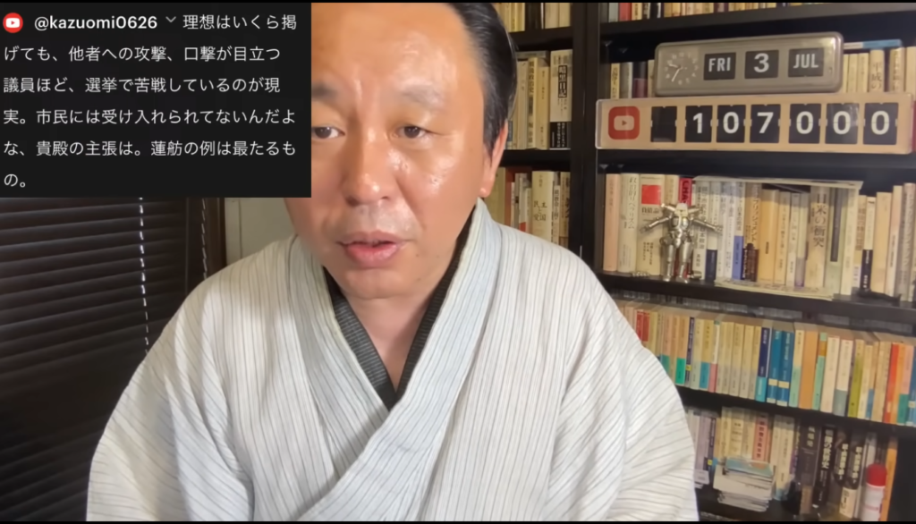 和服を着た菅野完が語りかける動画のスクリーンショット。左上には視聴者からのコメントが表示されている。